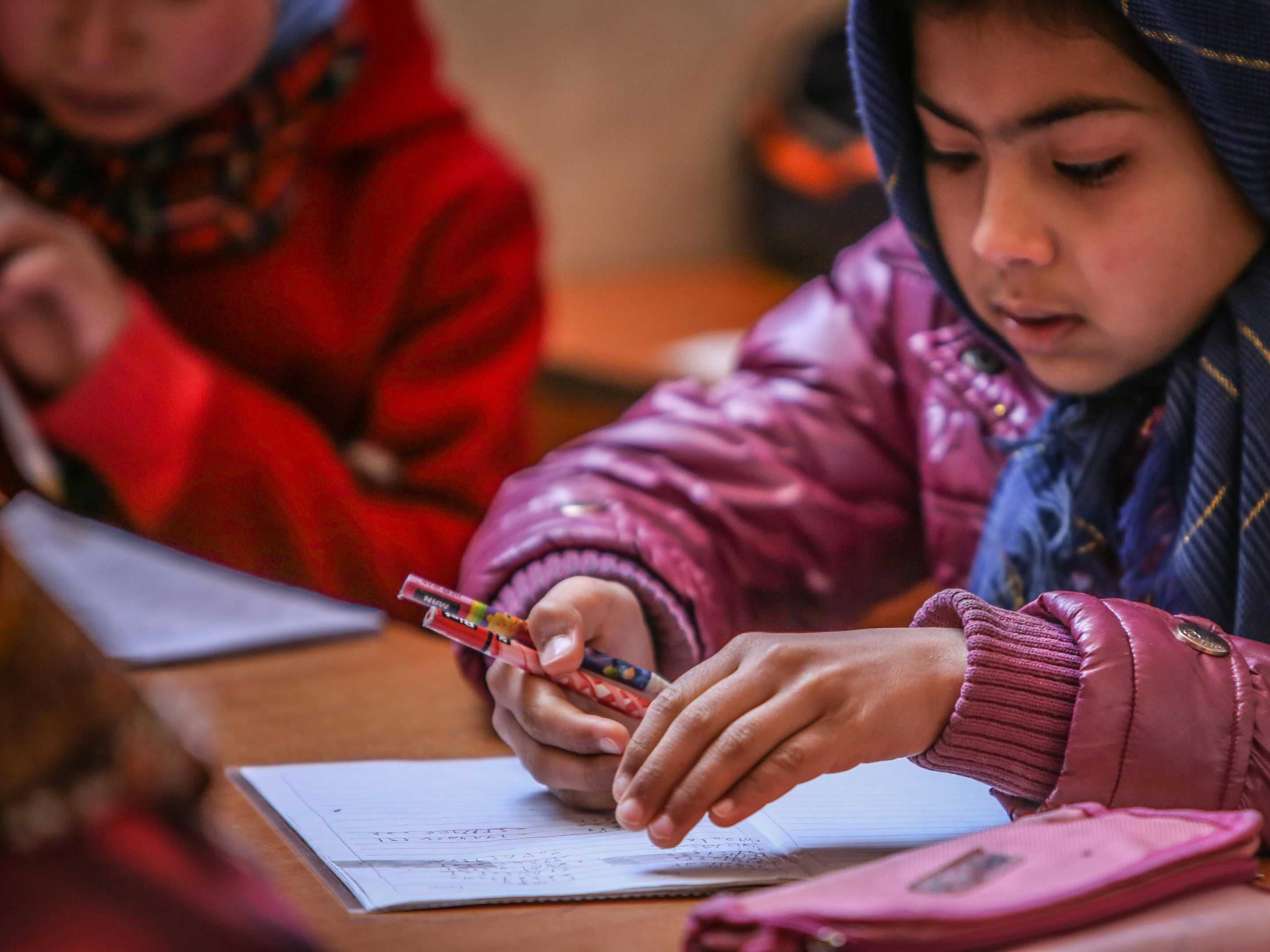 Afghan children engaged in their studies inside a classroom.